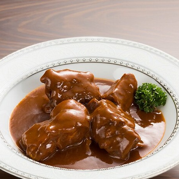 白い皿に盛られたたっぷり牛たんシチューと、添えられたパセリ