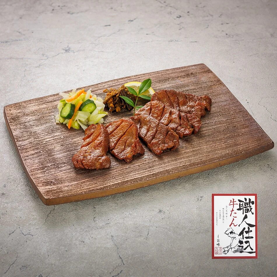 木の板皿に盛り付けた職人仕込牛たんの焼き上がりと、職人仕込牛たんの化粧箱