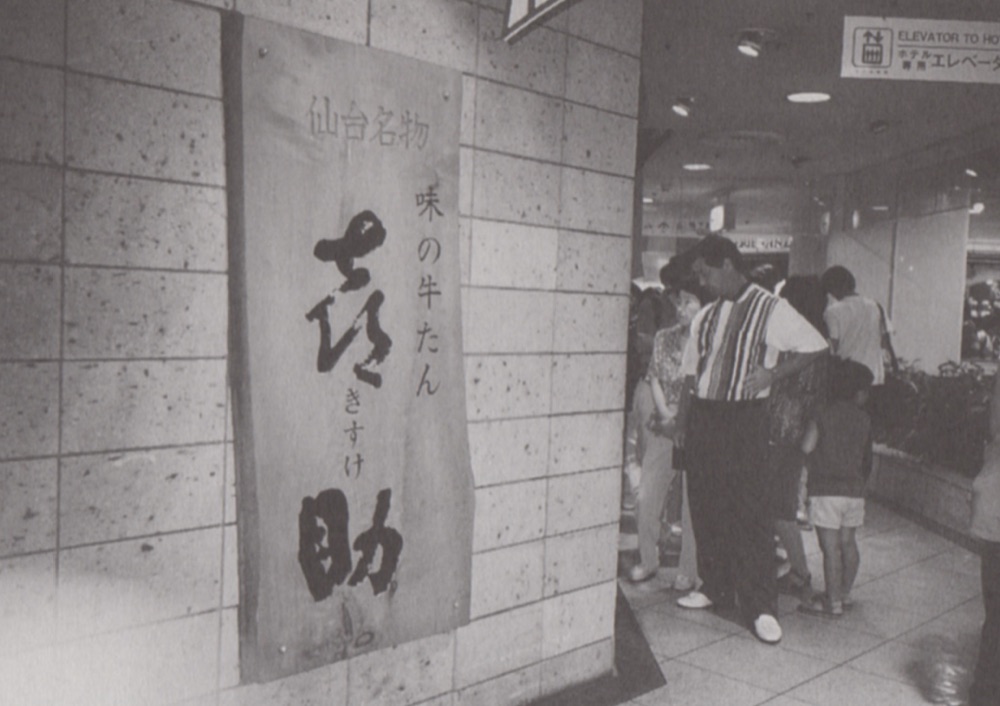 「仙台名物 味の牛たん 喜助」と墨書された木の看板が掲げられたエスパル店頭の白黒写真