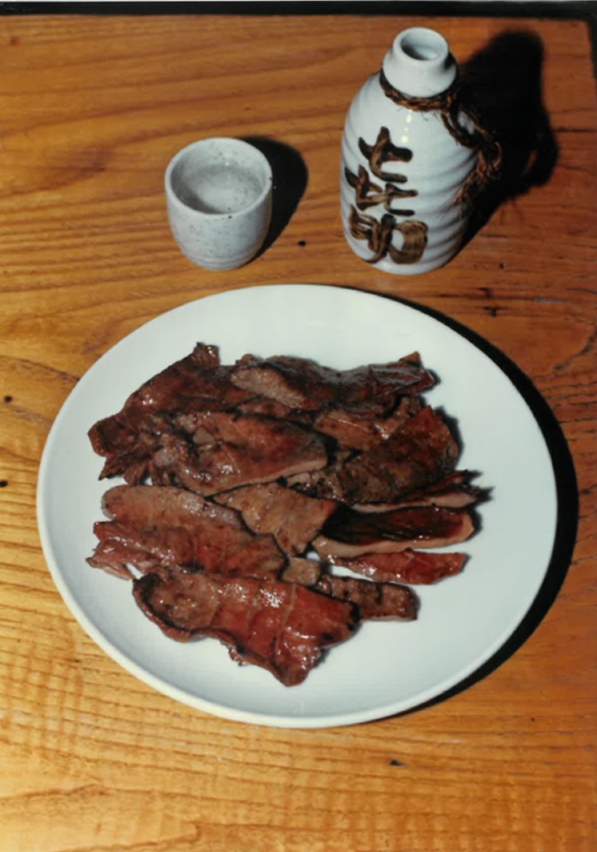 創業当時の牛たん焼きを盛った白い皿と、喜助の銘が入った徳利・ぐい呑み