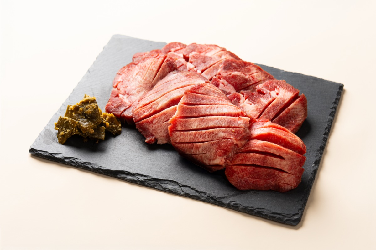 黒いスレート皿に盛った、焼く前の生牛たんのスライス。一枚ずつ切り込みが入っている
