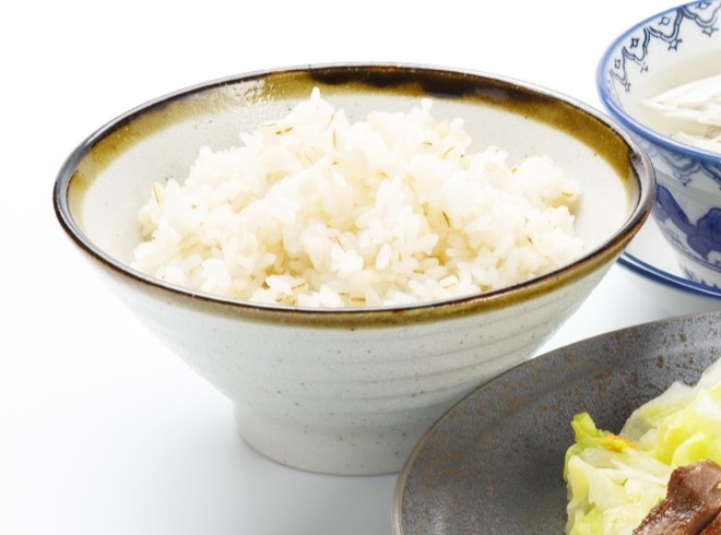 茶碗に盛った麦飯。米粒に混ざって押麦の筋が見える。奥にテールスープの碗が写っている