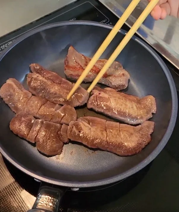 油をひかないフライパンに牛たんを並べ、箸を添えて焼きはじめたところ