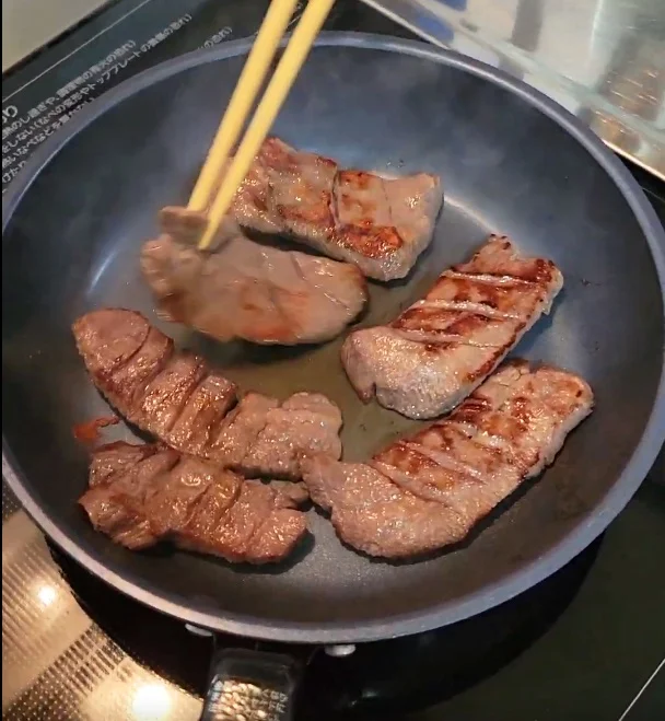 片面が焼き上がった牛たんを、箸で裏返しているところ